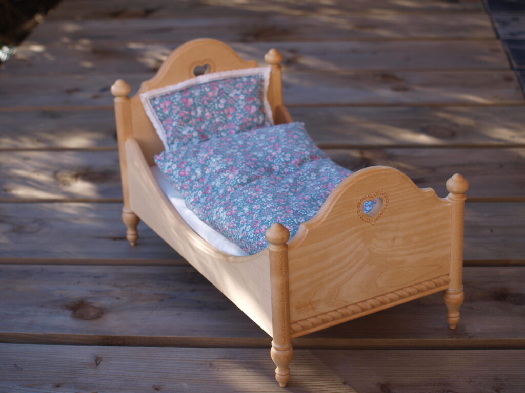 Kleines Holzbett mit Blümchen-Bettzeug als Sinnbild für den Schlafplatz