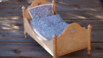 Kleines Holzbett mit Blümchen-Bettzeug als Sinnbild für den Schlafplatz