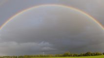 Regenbogen über einer weiten Feldlandschaft