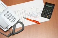 Schreibtisch mit Telefon, Taschenrechner und Diagrammen zur Beratung