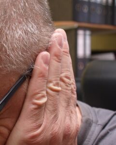 Mann hält sich das Ohr – Sinnbild für Tinnitus und Hörsturz