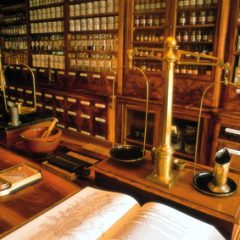 Historische Apotheke mit Messingwaagen und aufgeschlagenem Buch